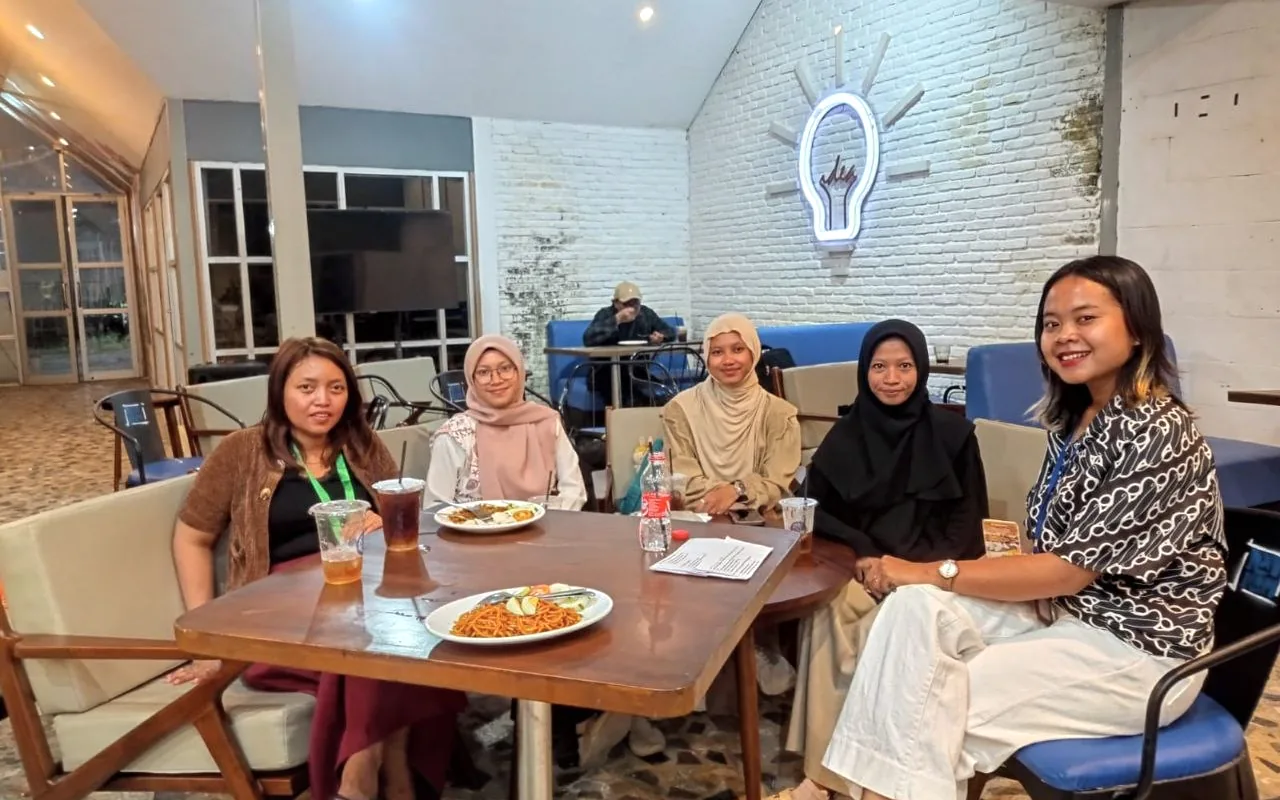 Lima peserta duduk bersama di meja dalam ruang komunitas.